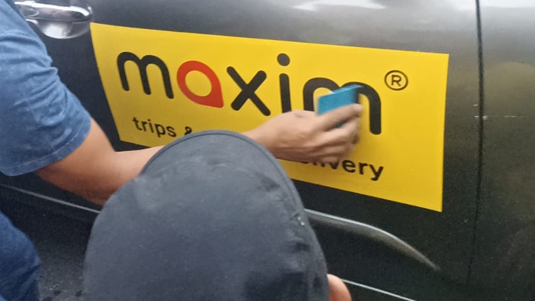 Pemasangan stiker sebagai simbol Maxim dan sopir mobil rental sepakat beroperasi bersama, Selasa (14/5/2024). Foto: Eka/ Papua60detik