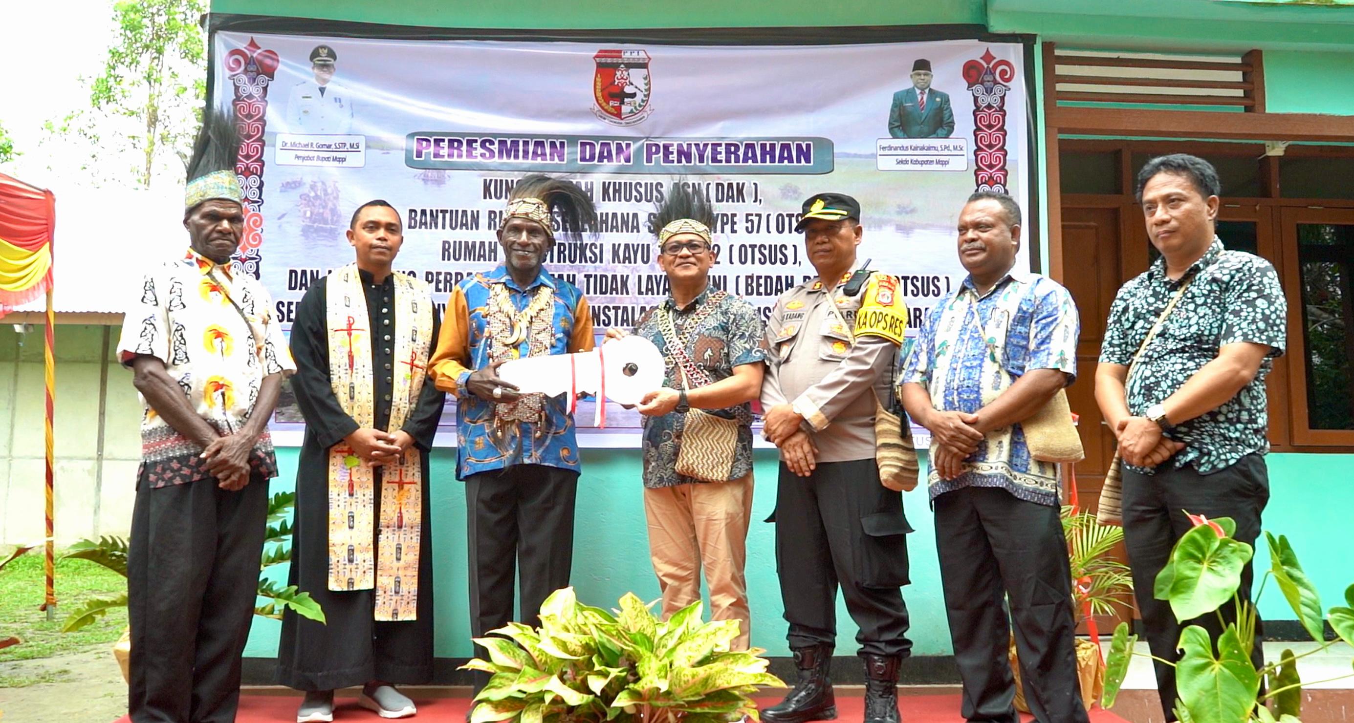 Pj Bupati Mappi, Michael R. Gomar saat menyerahkan kunci kepada penerima bantuan rumah layak huni. Foto: Humas Pemkab Mappi.